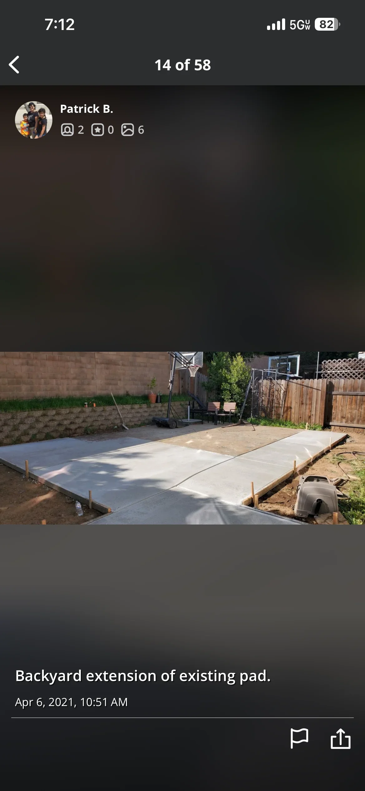 Newly poured concrete pad extension in backyard with wooden stakes and existing pad