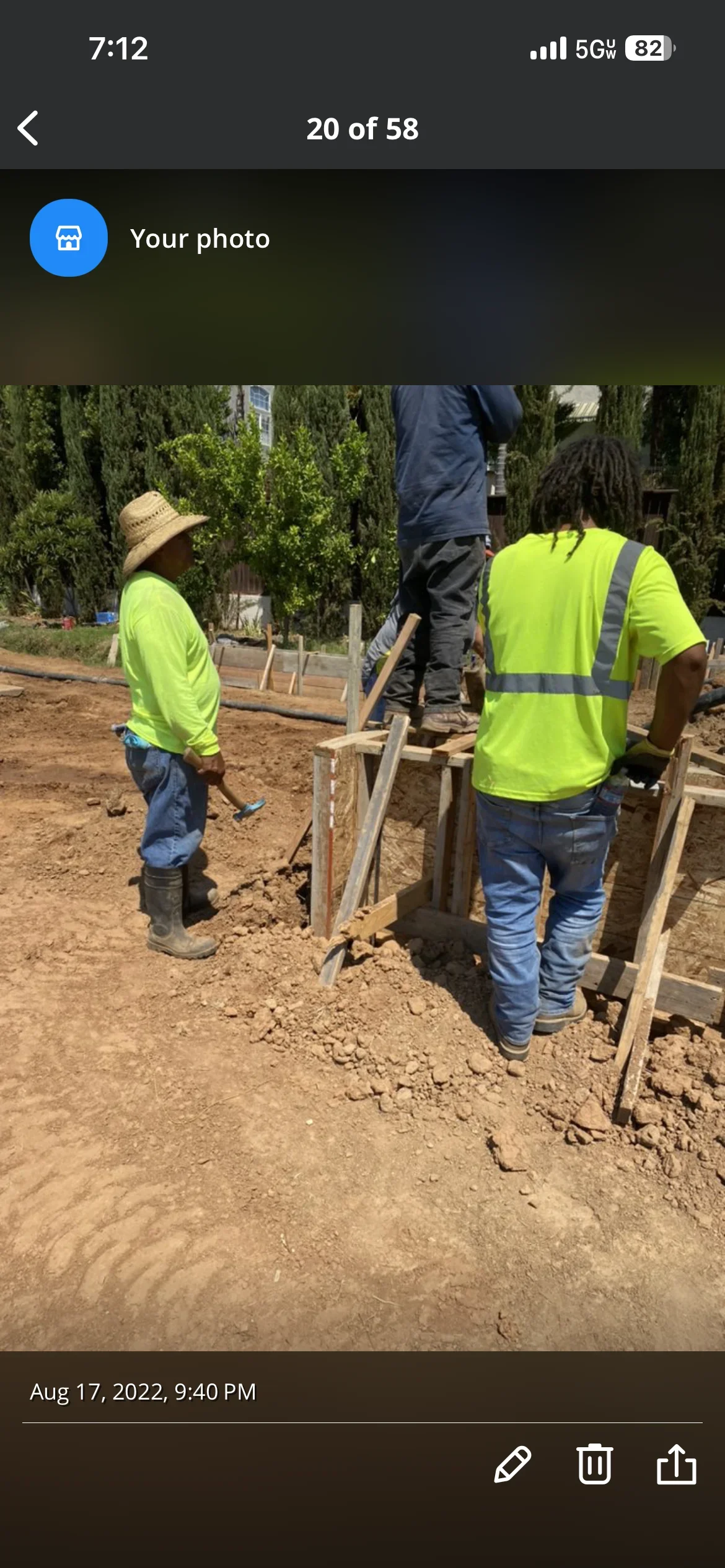 Two workers in safety vests preparing excavated foundation site with wooden forms