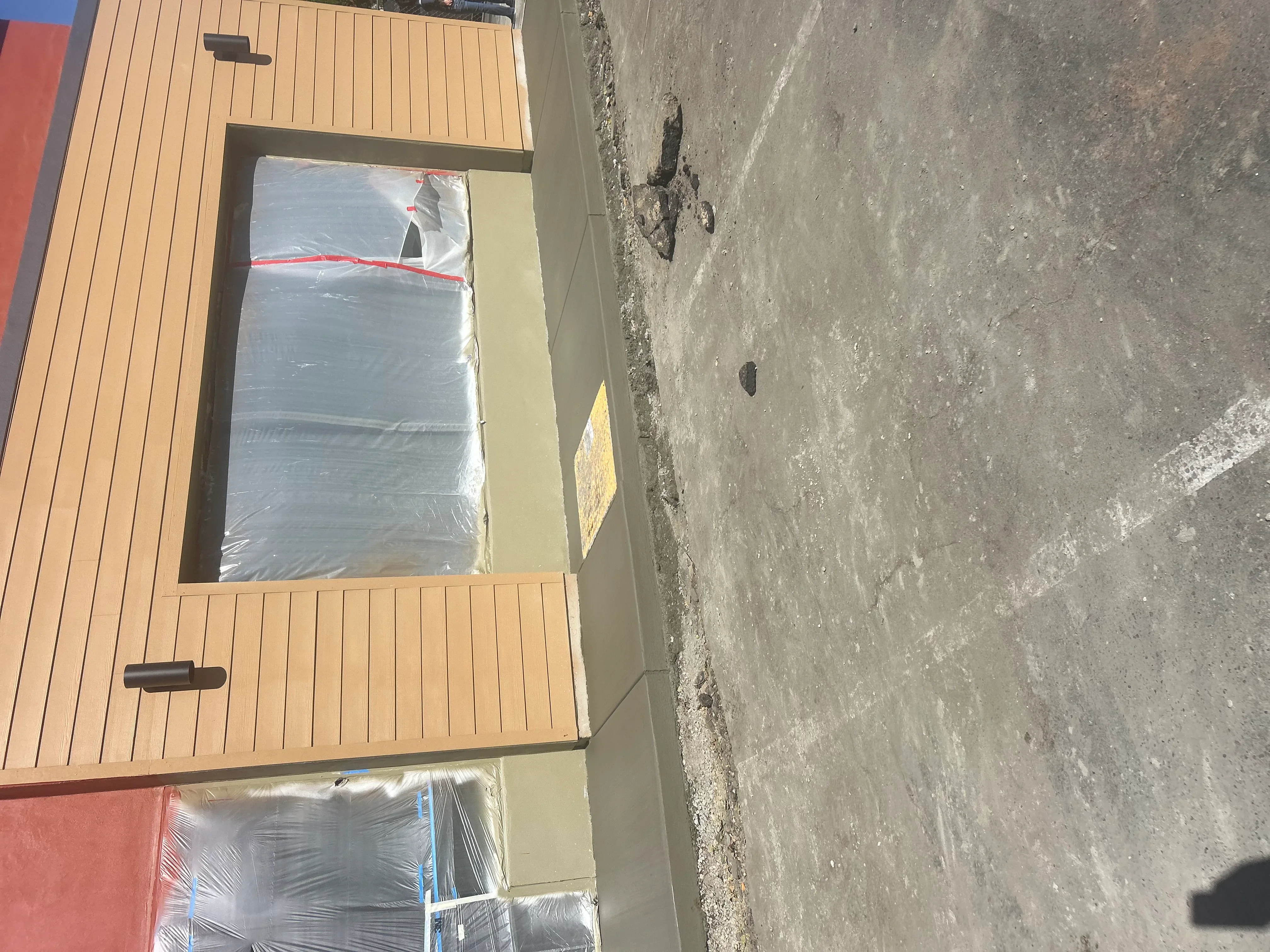 Composite deck installation over concrete foundation with protective wrapping and framing