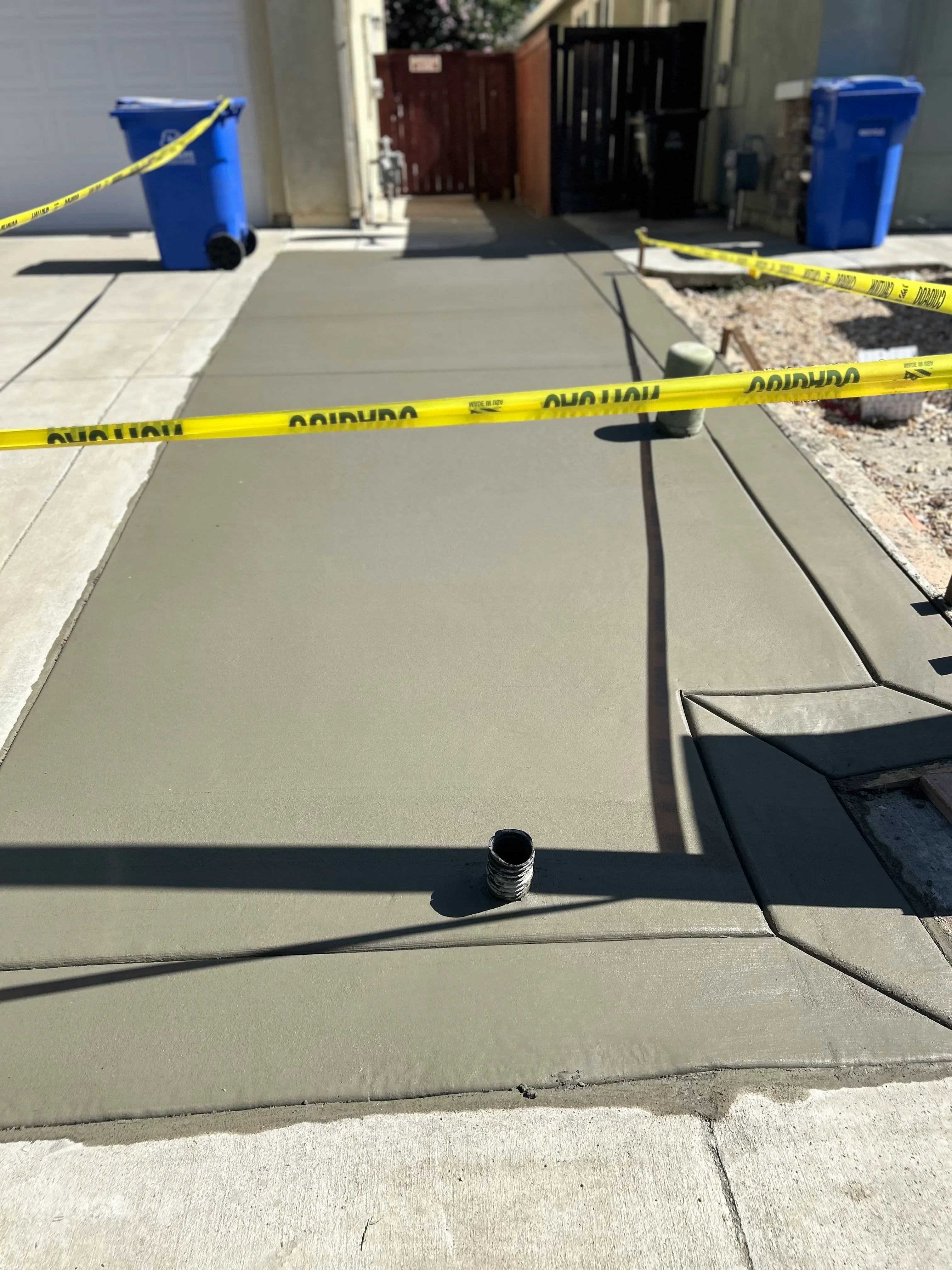 Newly poured concrete driveway with control joints and drainage slope during curing phase