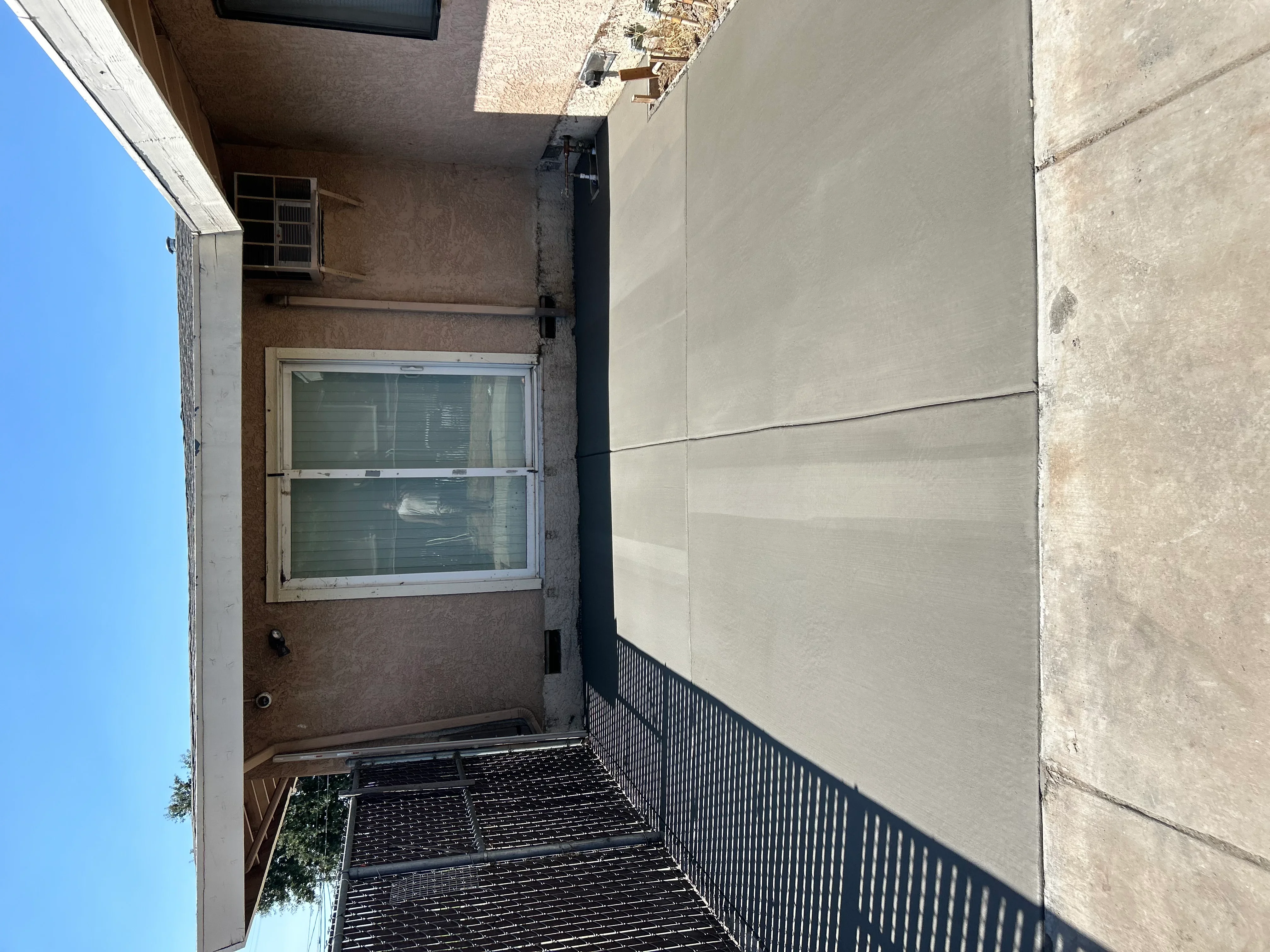 Finished concrete patio with metal railing and control joints in residential setting