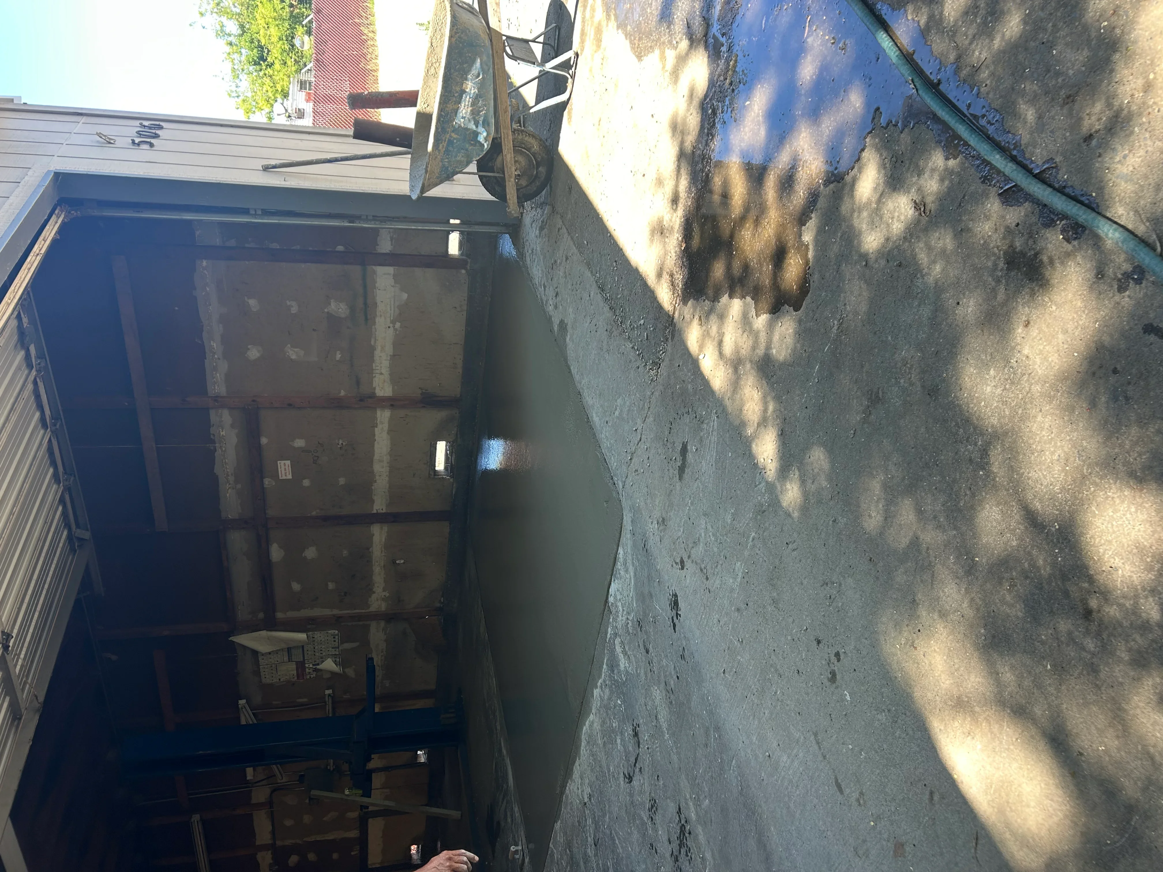 Clean concrete driveway next to weathered building wall with blue door
