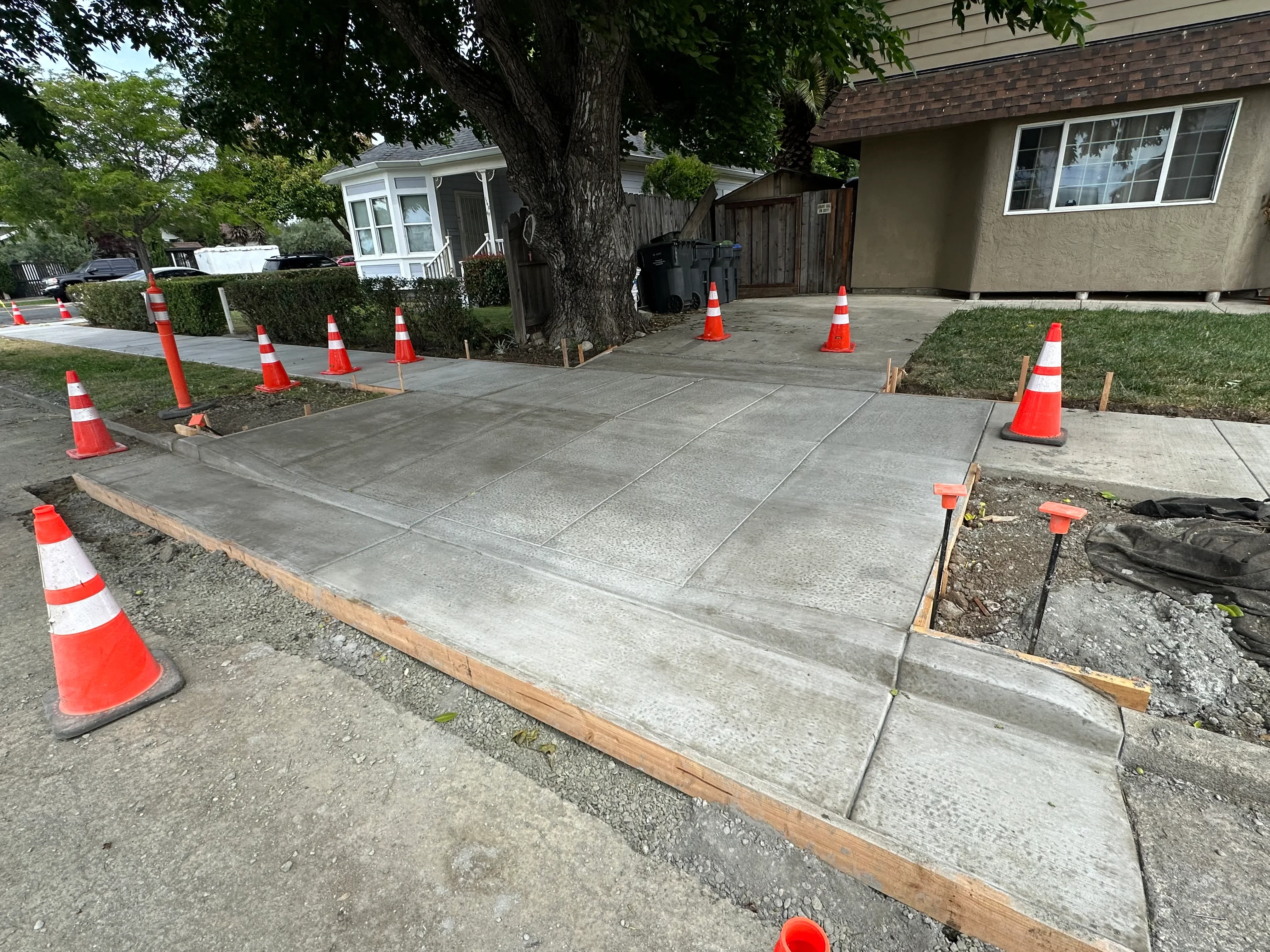 New concrete driveway with control joints during curing, safety cones marking work area