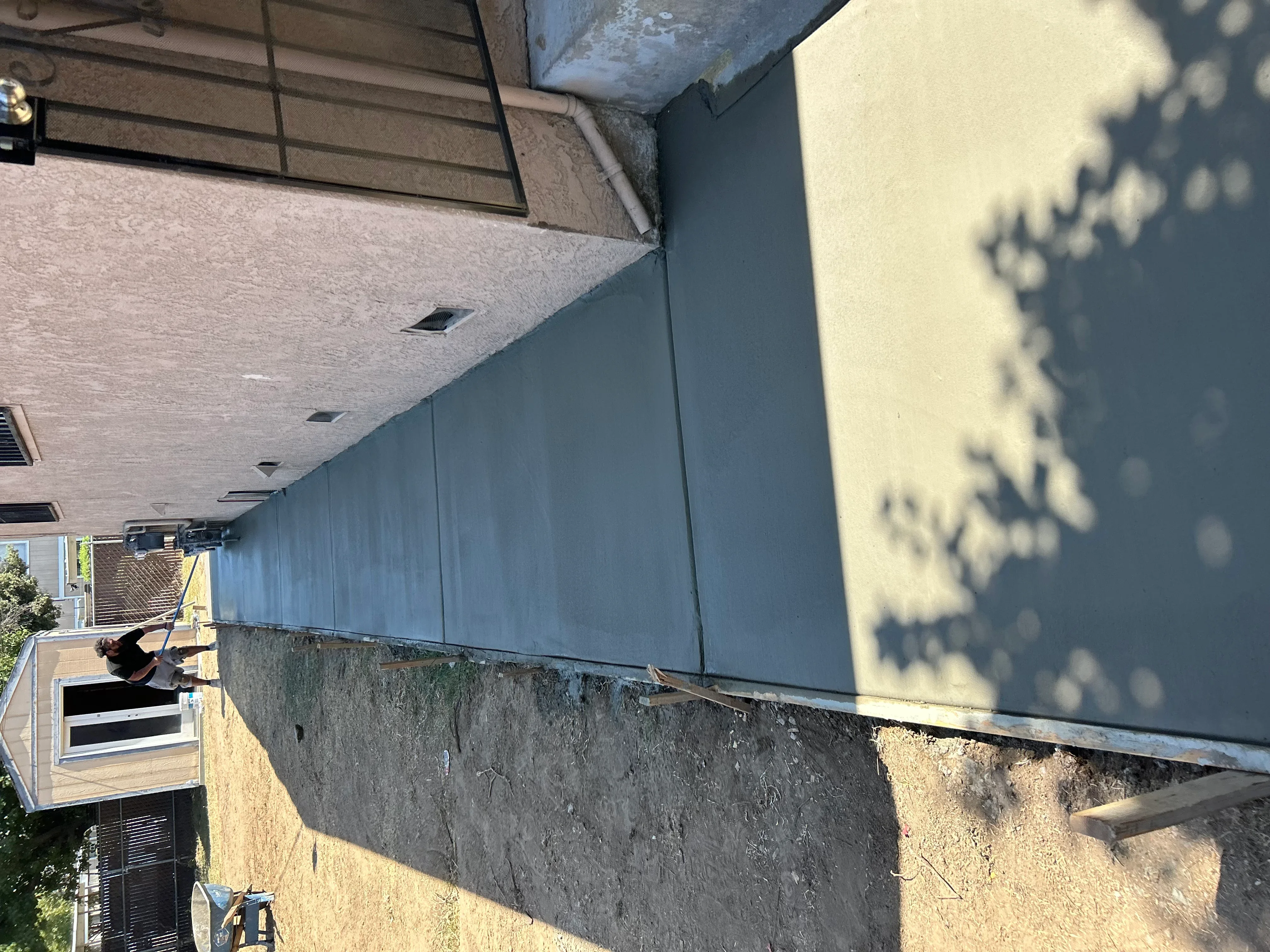 Newly poured concrete foundation and driveway with gray concrete walls and finished surface