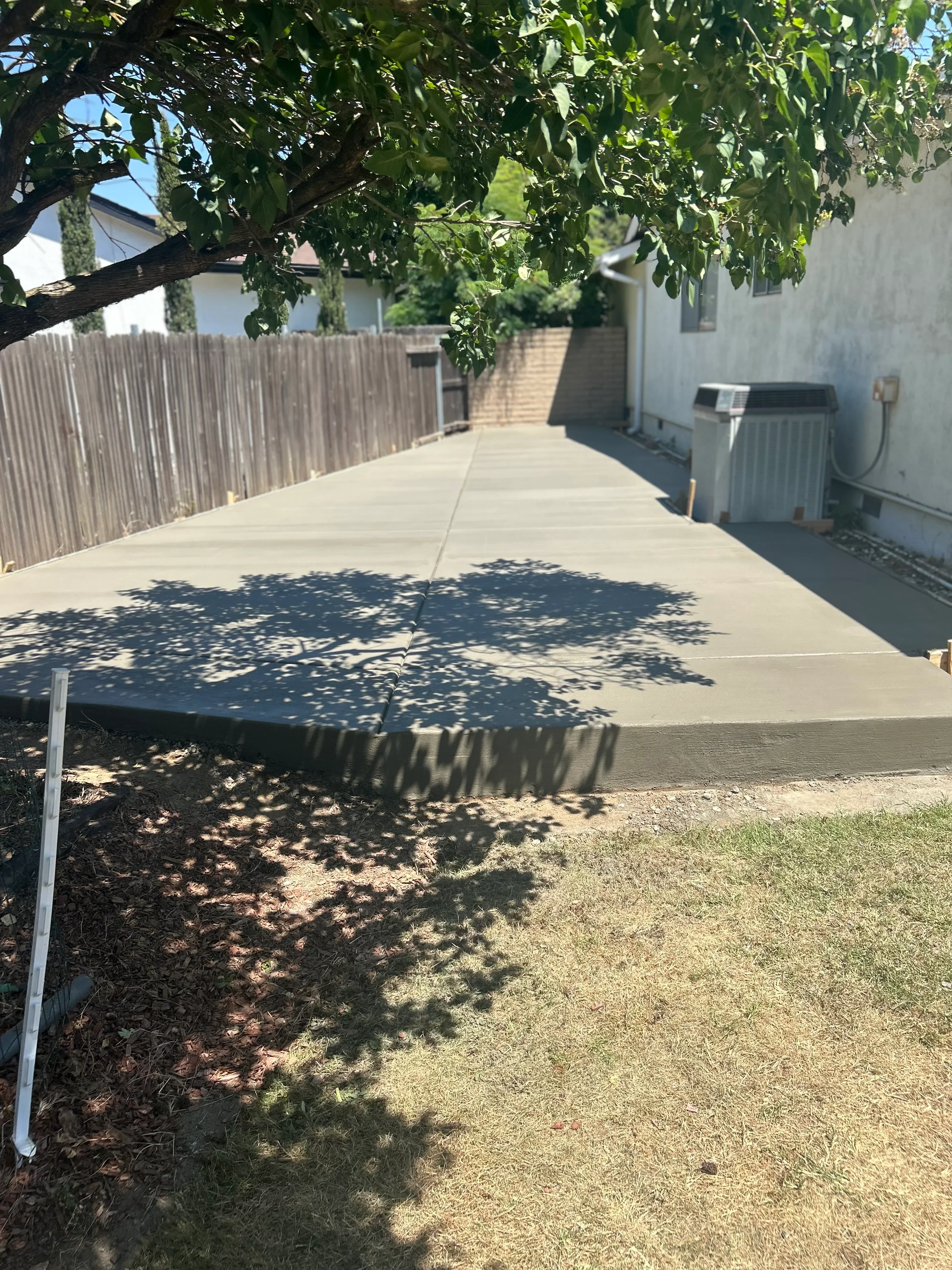 New concrete driveway and walkway with metal edging in residential backyard