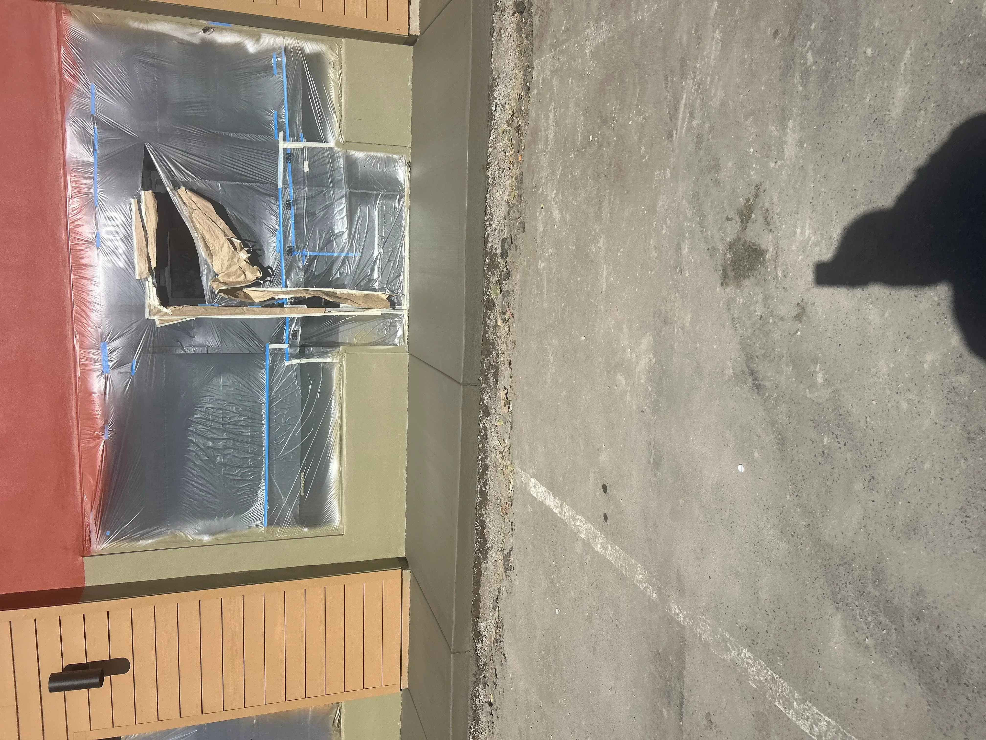 Interior concrete floor with protective plastic sheeting and blue tape during preparation phase