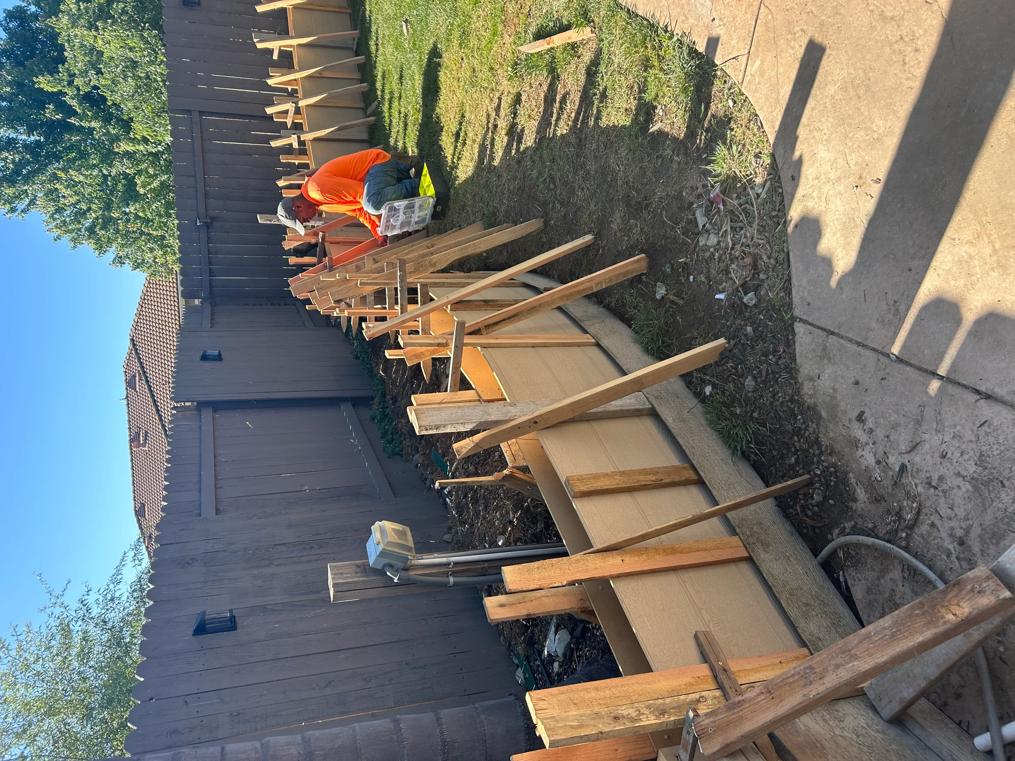 Worker in orange safety vest installing concrete footings for residential deck construction