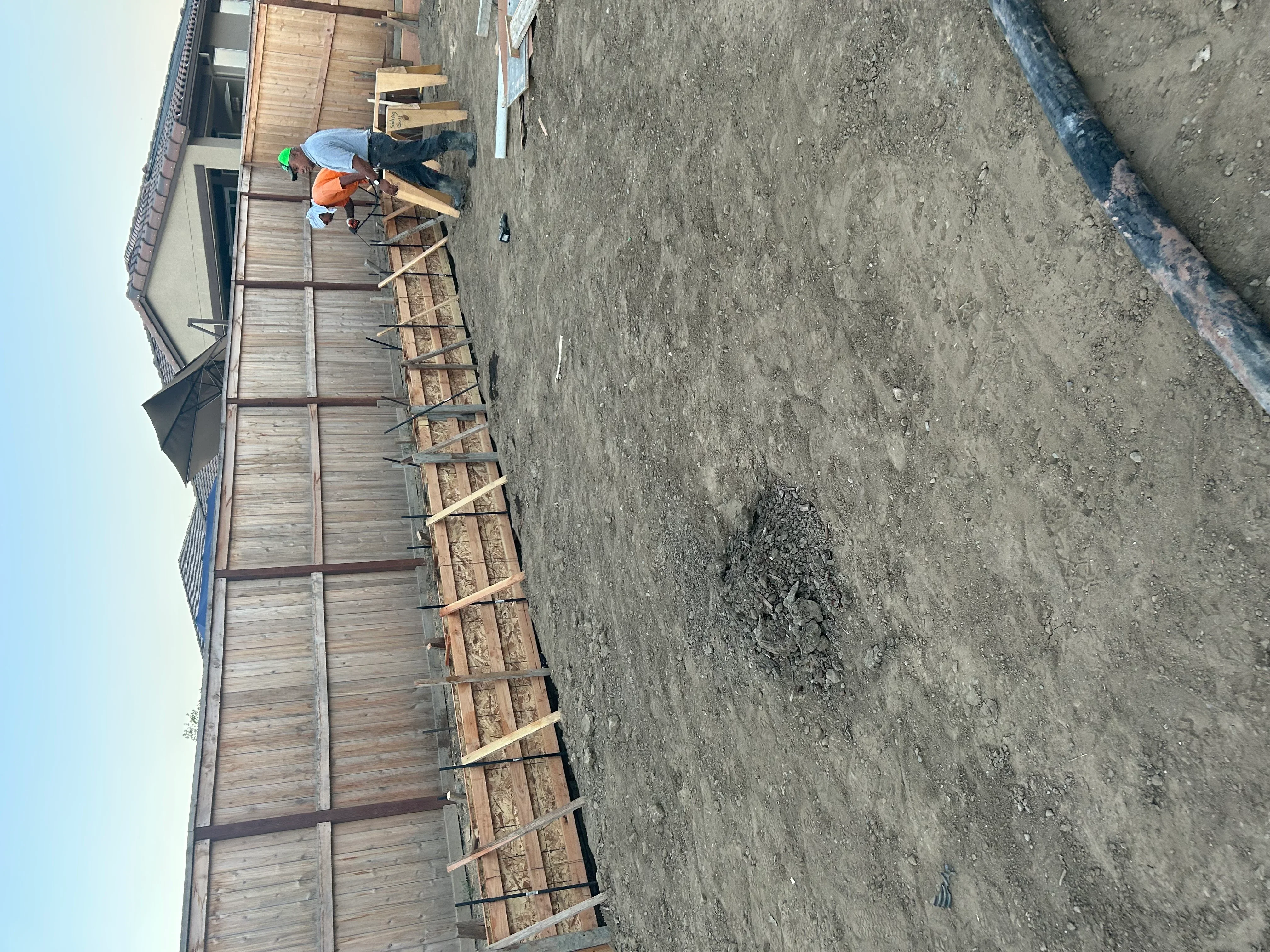 Worker installing rebar grid on concrete foundation with wooden forms visible