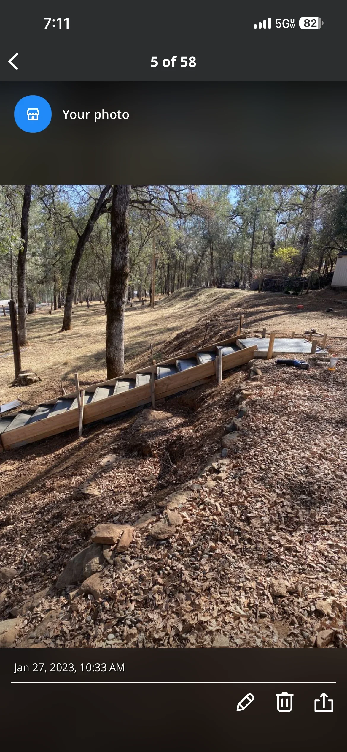 Concrete retaining wall with wooden forms on sloped terrain among oak trees