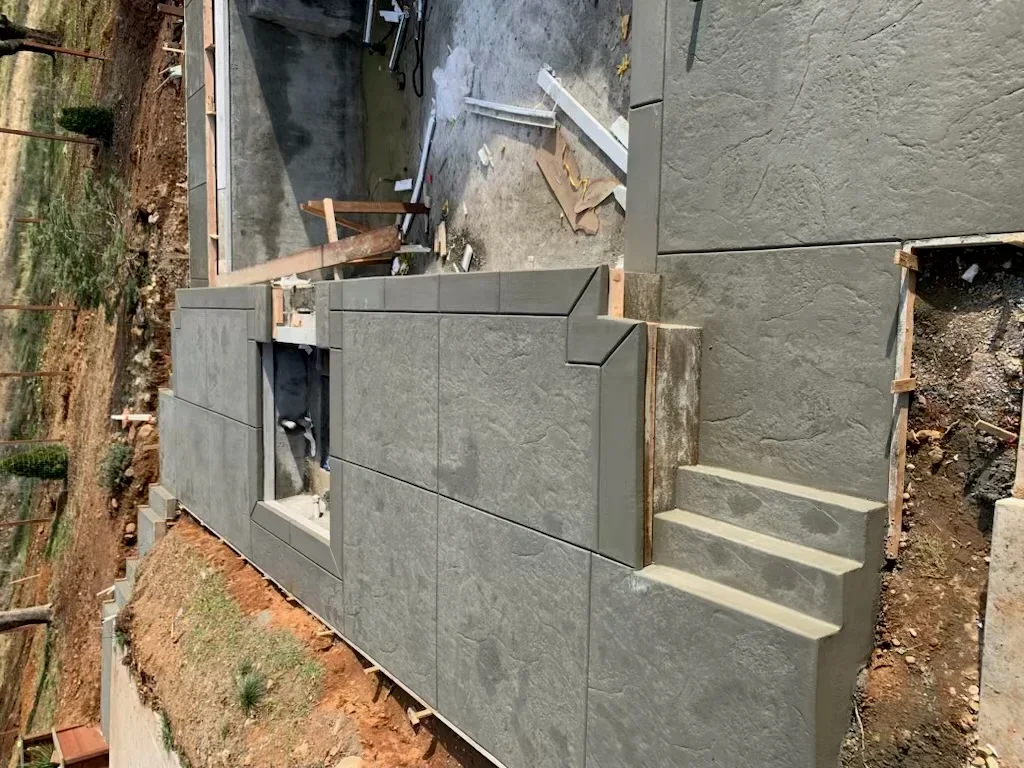 Textured concrete retaining wall with integrated steps during construction in Sacramento